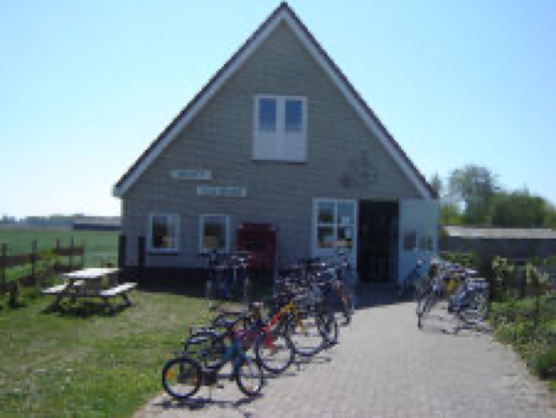 Huurfietsen voor de deur van Werner's Fietsverhuur, met een picknicktafel op het gras